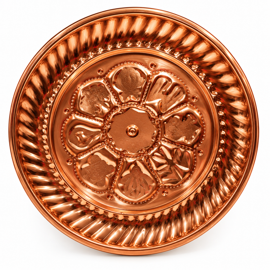 A round copper-colored decorative tray with embossed floral and geometric patterns, photographed from directly above on a white background. Tika Thali